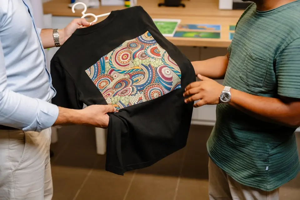 Black T-shirt printed with a colourful design, shown to a customer