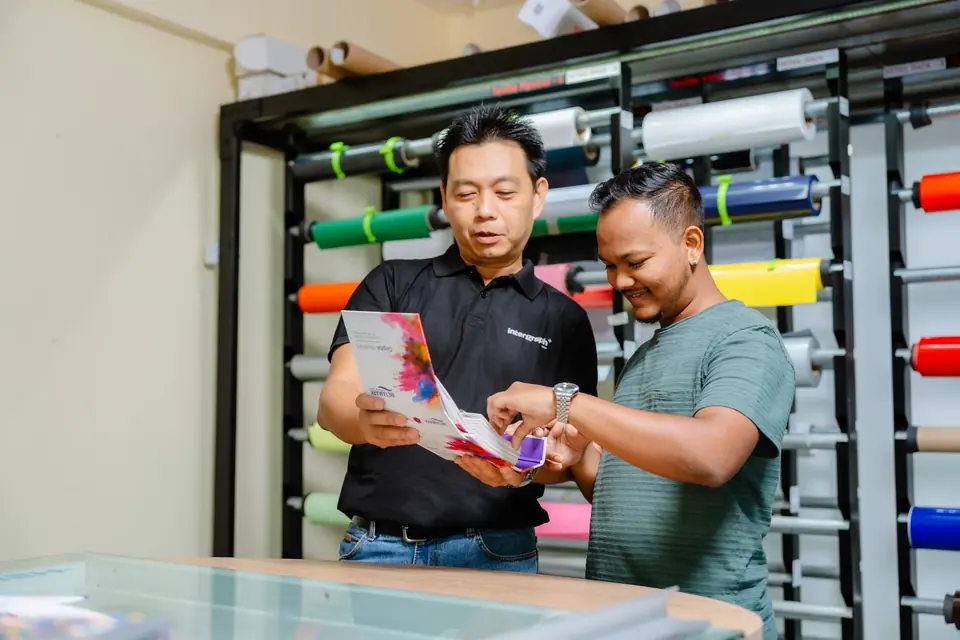 Customer consultation in front of a rack of coloured vinyl rolls